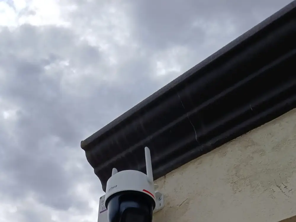 Cámara Dahua PTZ con antena montada en la esquina alta de un muro, junto a un portón
